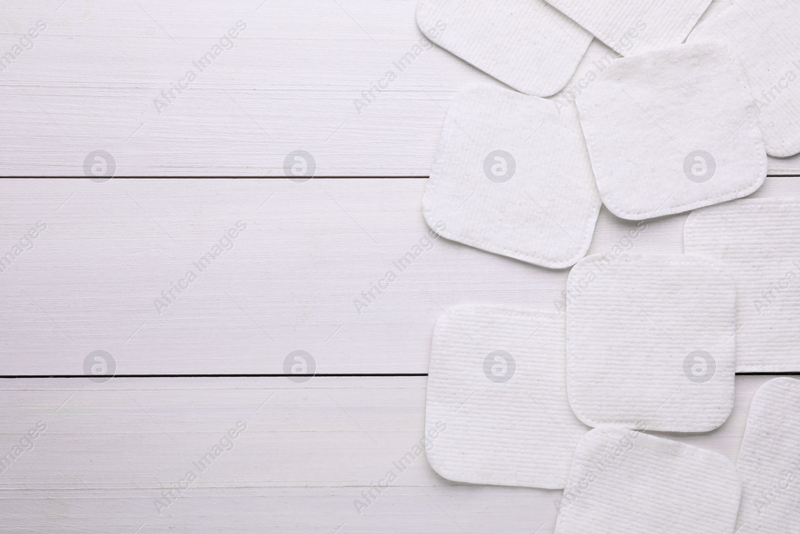 Photo of Clean cotton pads on white wooden table, flat lay. Space for text