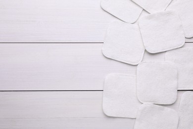 Clean cotton pads on white wooden table, flat lay. Space for text