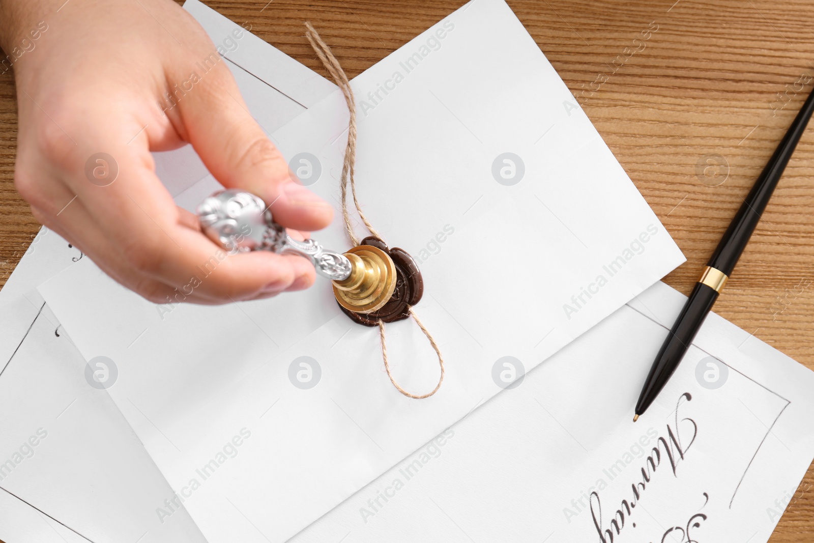 Photo of Male notary sealing document at table, top view