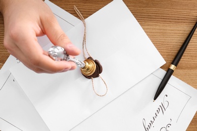 Male notary sealing document at table, top view