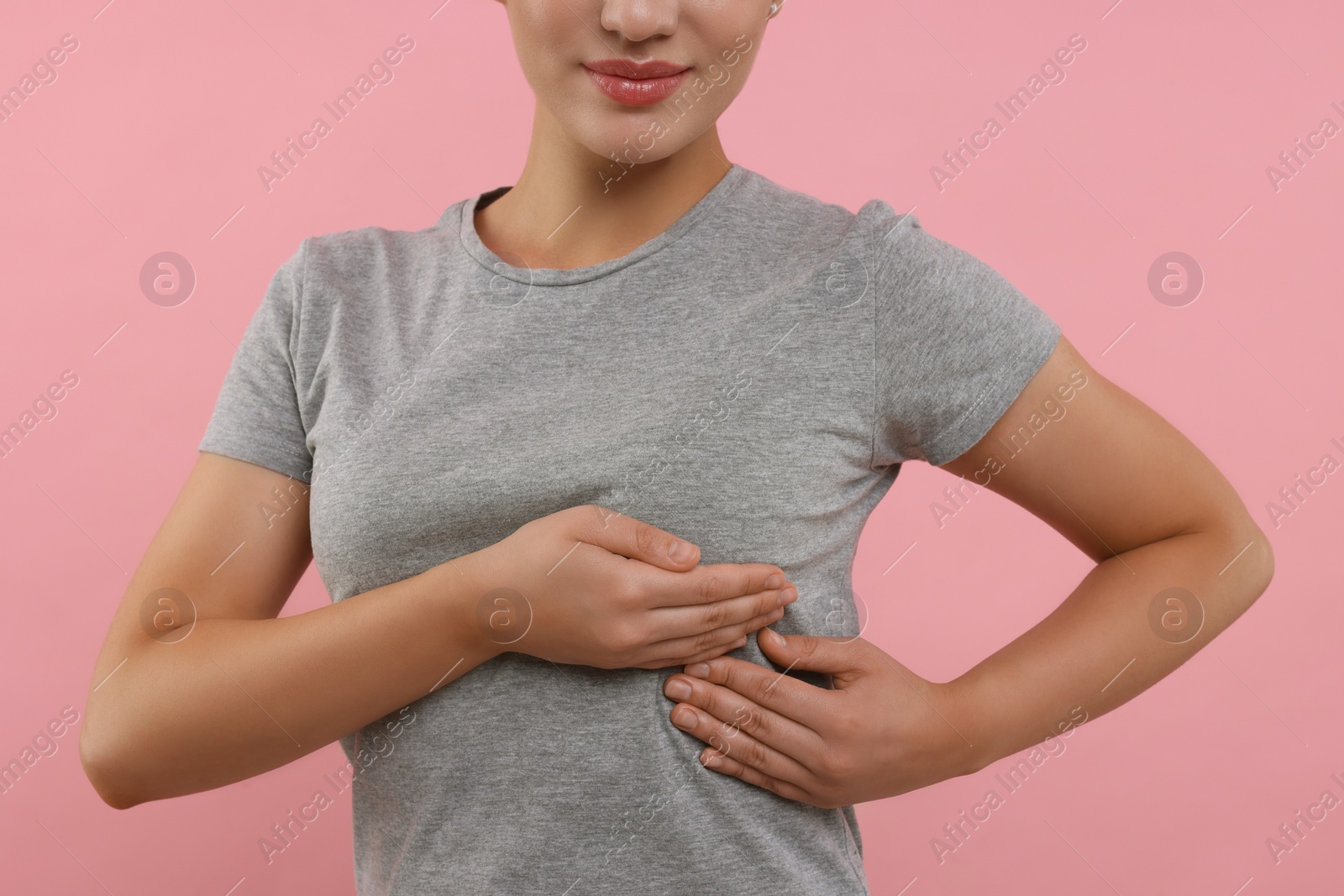 Photo of Woman doing breast self-examination on pink background, closeup