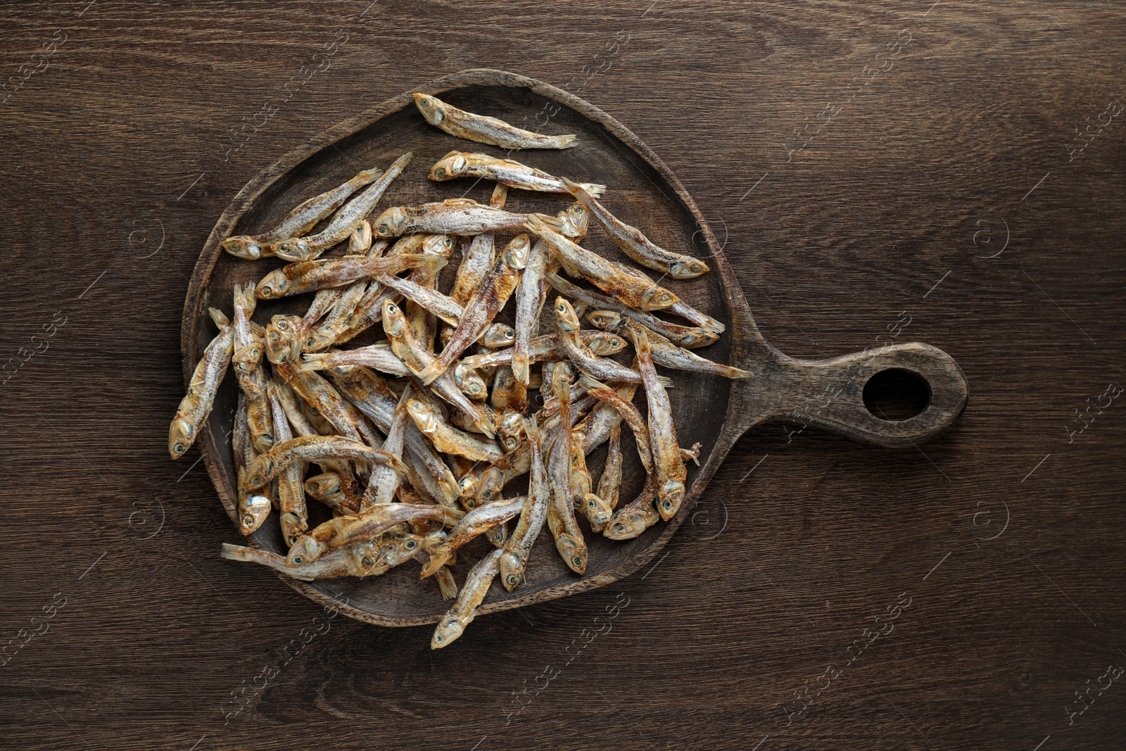 Photo of Delicious dried anchovies on wooden table, top view