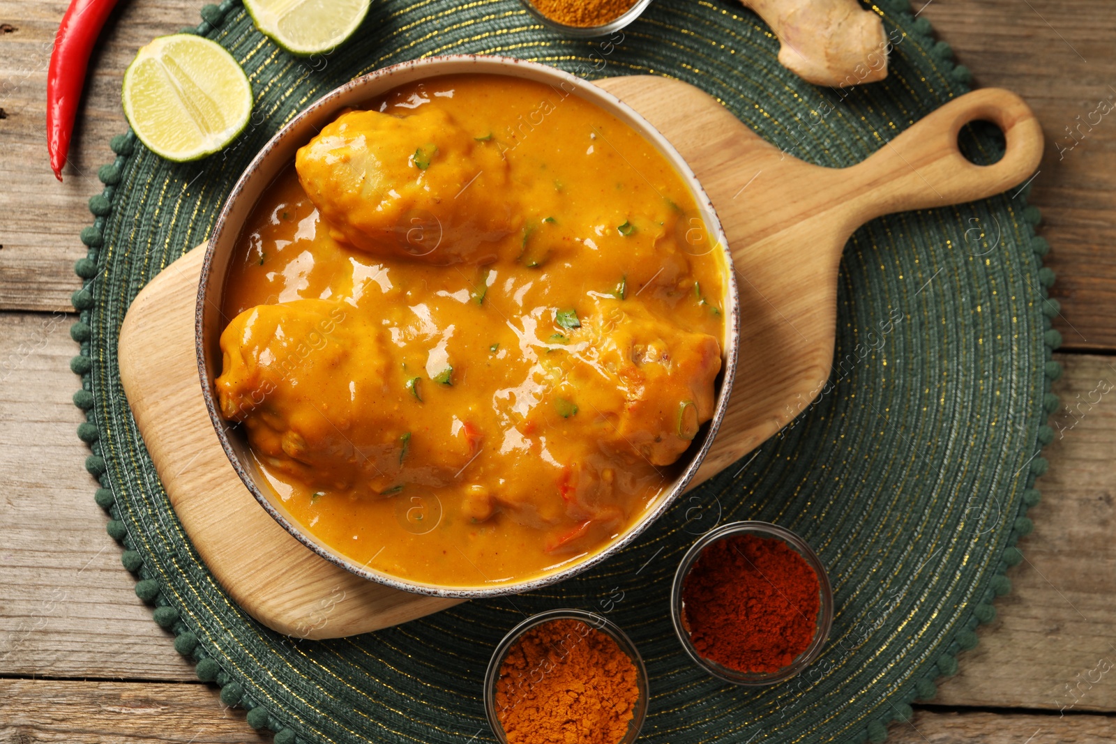 Photo of Tasty chicken curry and ingredients on wooden table, flat lay