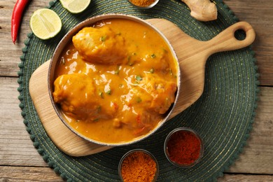 Tasty chicken curry and ingredients on wooden table, flat lay