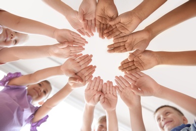 Little children putting their hands together indoors, view from below. Unity concept