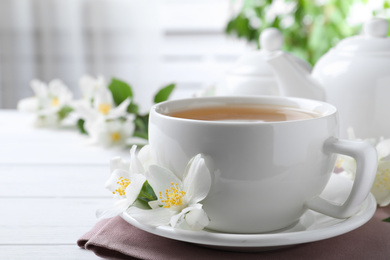 Cup of tea and fresh jasmine flowers on white wooden table