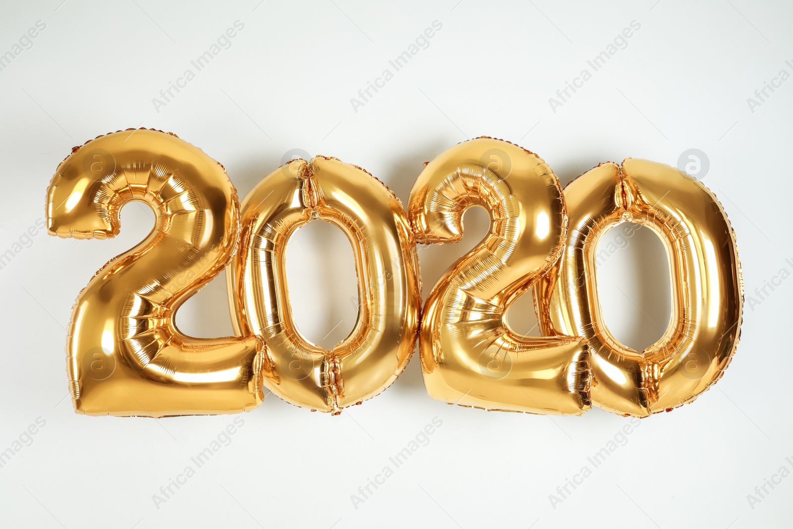 Photo of Golden balloons for party decoration on white background. 2020 New Year celebration