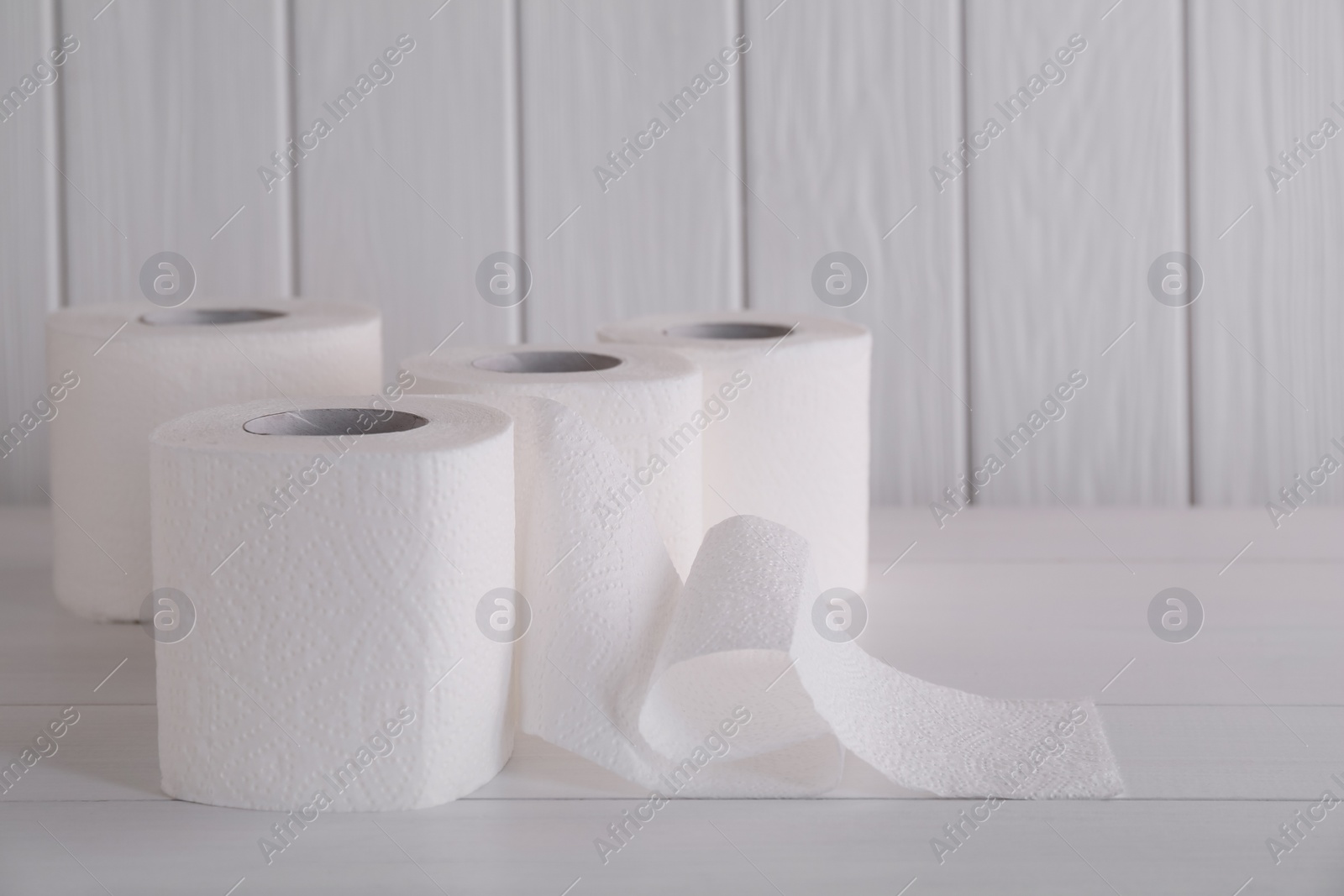 Photo of Many soft toilet paper rolls on white wooden table. Space for text