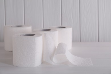 Photo of Many soft toilet paper rolls on white wooden table. Space for text