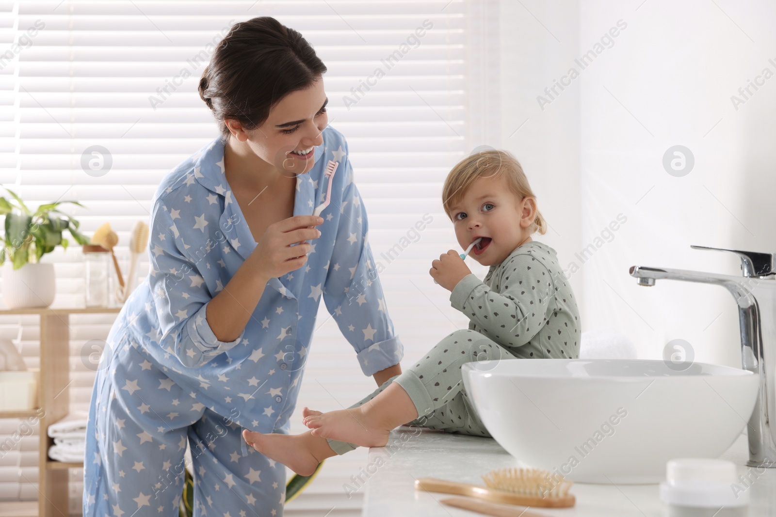 Photo of Mother and her daughter brushing teeth together in bathroom