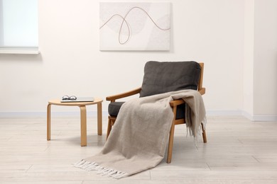 Comfortable armchair, blanket and side table in room