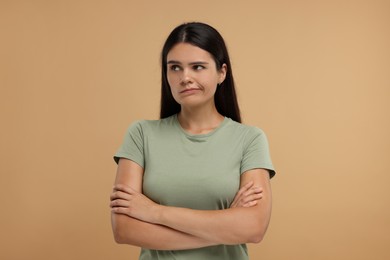 Portrait of resentful woman with crossed arms on beige background