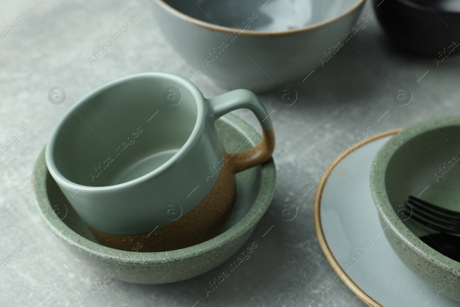 Photo of Stylish empty dishware and cup on light grey table, closeup