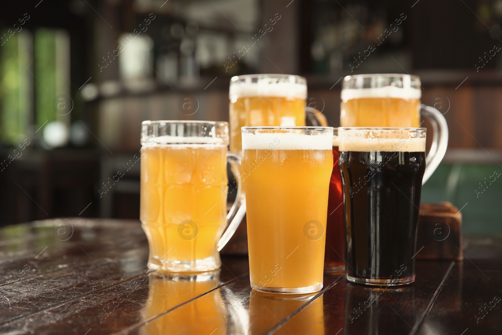 Photo of Glasses of tasty beer on wooden table in bar