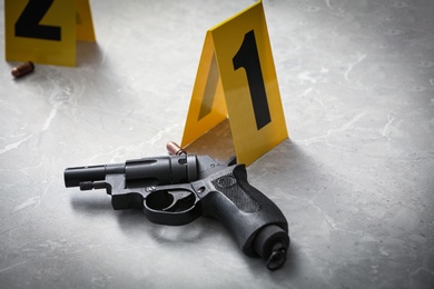 Photo of Handgun and crime scene marker on light grey marble table