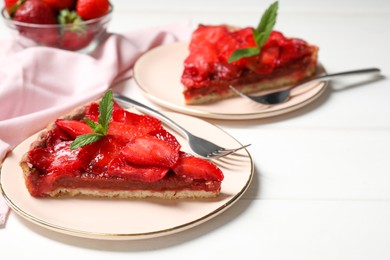 Photo of Piece of delicious strawberry tart with mint on white wooden table. Space for text