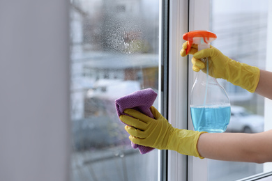 Photo of Woman cleaning window at home, closeup. Household chores