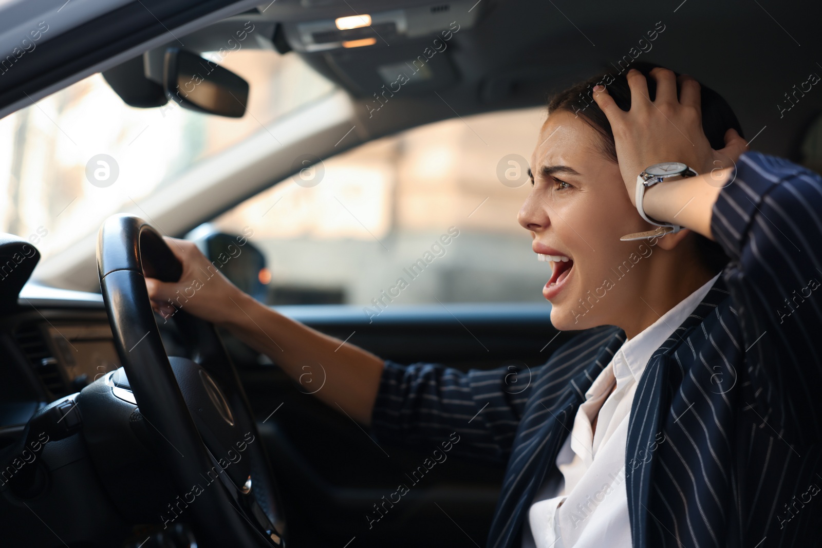 Photo of Angry driver screaming in her car. Stuck in traffic jam