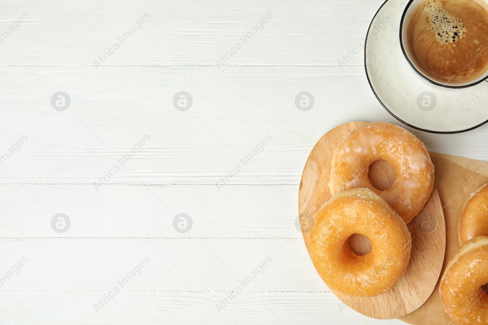 Photo of Delicious donuts and coffee on white wooden table, flat lay. Space for text