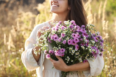 Photo of Woman holding bouquet of beautiful wild flowers outdoors, closeup