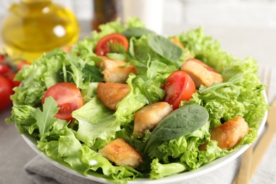 Photo of Delicious salad with chicken, cherry tomato and spinach on table, closeup