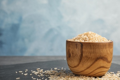 Bowl with raw unpolished rice on table. Space for text