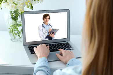 Woman using laptop for online consultation with mature female doctor, closeup 