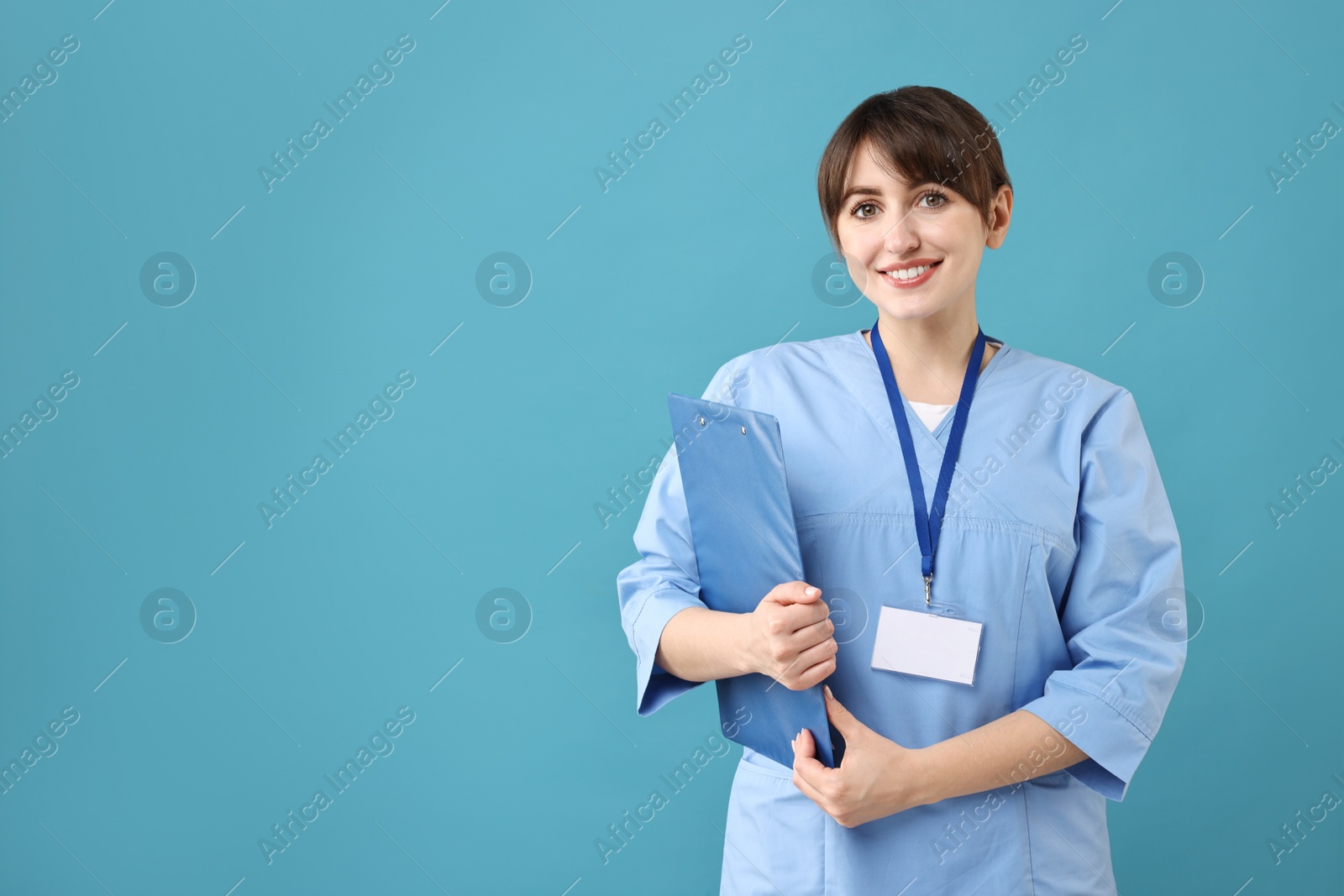 Photo of Portrait of smiling medical assistant with clipboard on light blue background. Space for text