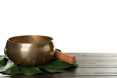 Photo of Golden singing bowl, mallet and monstera leaf on wooden table against white background, space for text