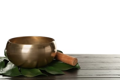 Golden singing bowl, mallet and monstera leaf on wooden table against white background, space for text