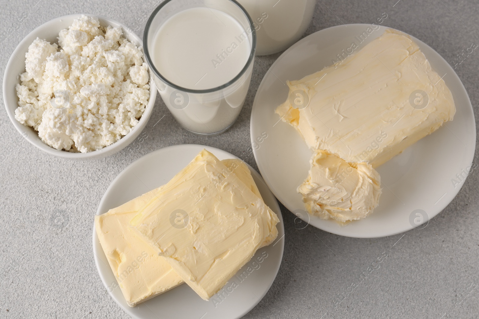 Photo of Tasty homemade butter and dairy products on white textured table, flat lay