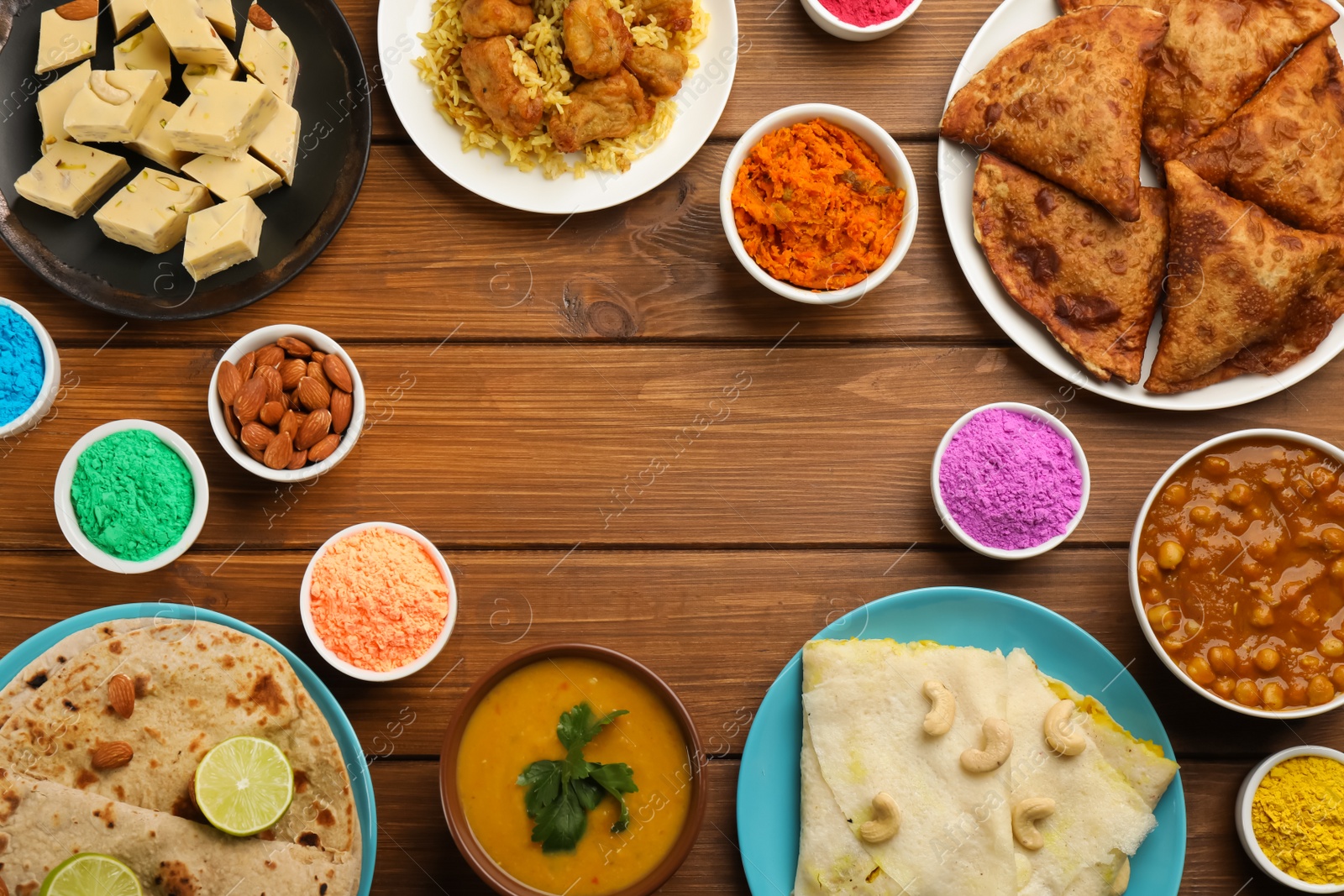 Photo of Frame of traditional Indian food and color powders on wooden table, flat lay with space for text. Holi festival celebration