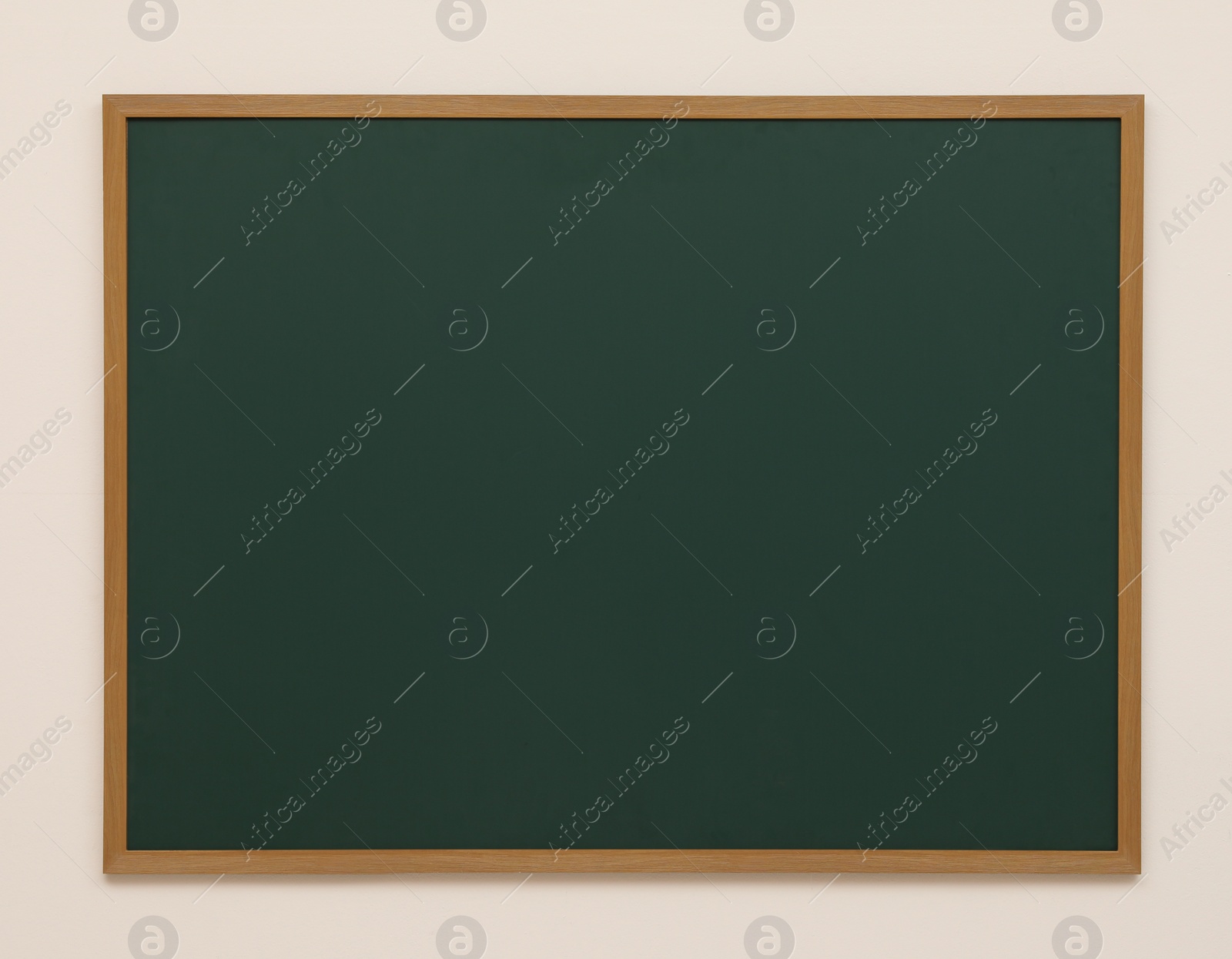 Photo of Clean green chalkboard hanging on white wall