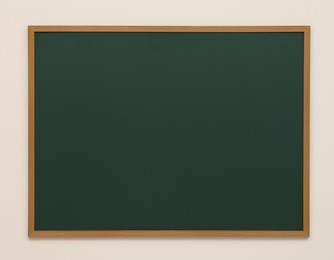 Clean green chalkboard hanging on white wall
