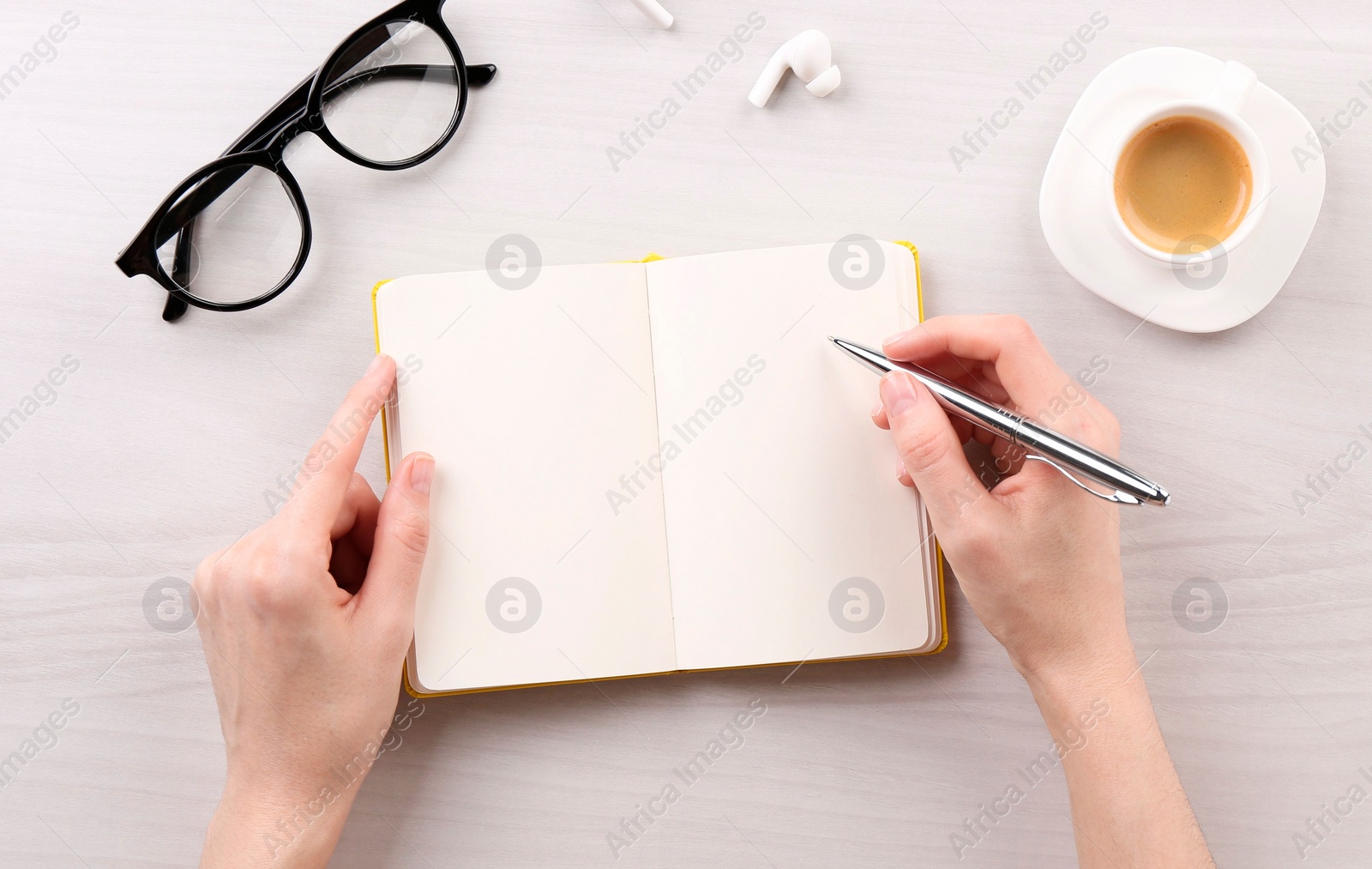 Photo of Woman with notebook and pen at white wooden table, top view. Space for text