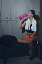 Beautiful woman drinking water in locker room