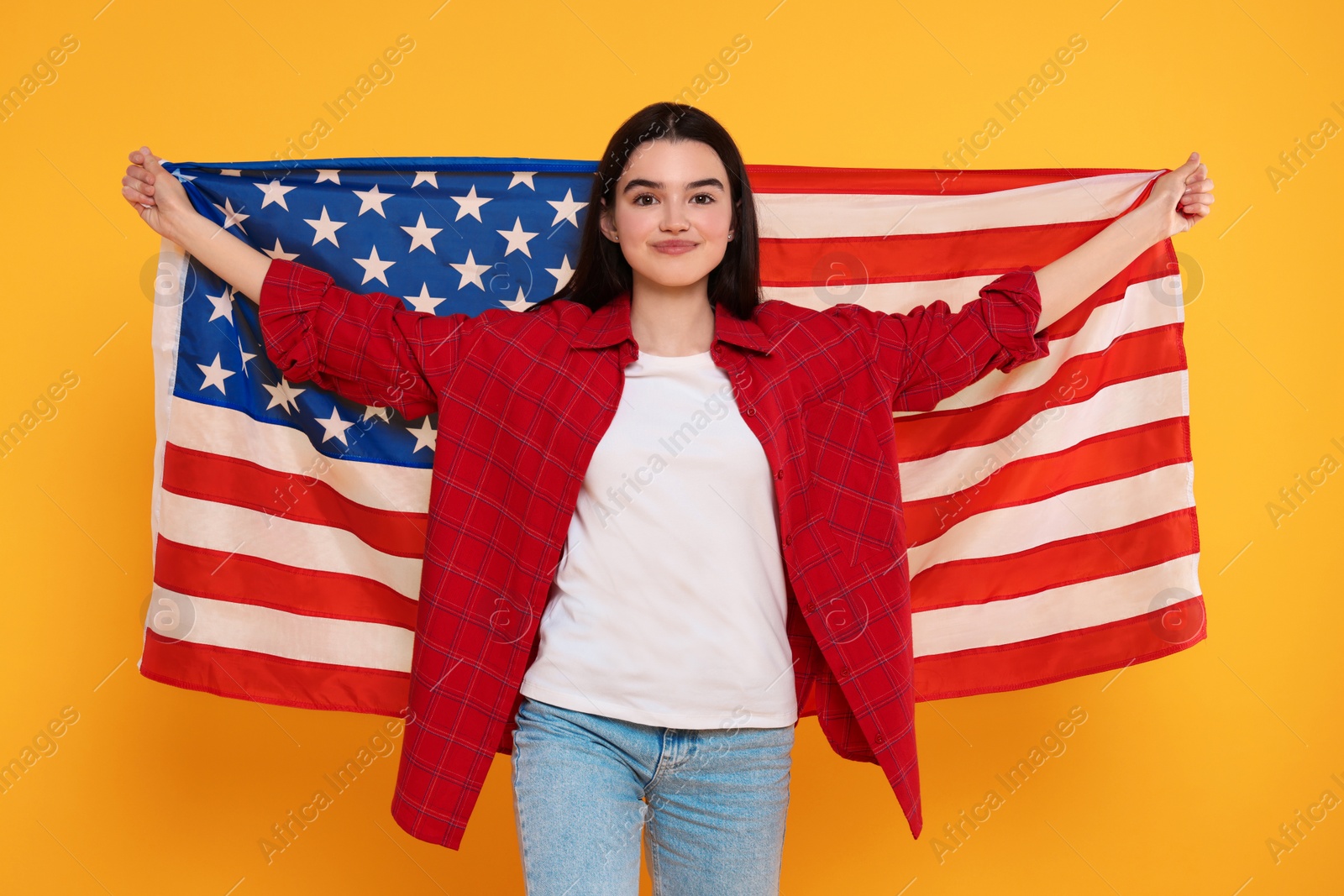 Photo of 4th of July - Independence Day of USA. Happy girl with American flag on yellow background