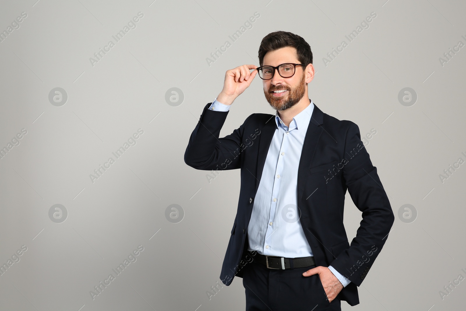 Photo of Handsome real estate agent in nice suit on grey background, space for text