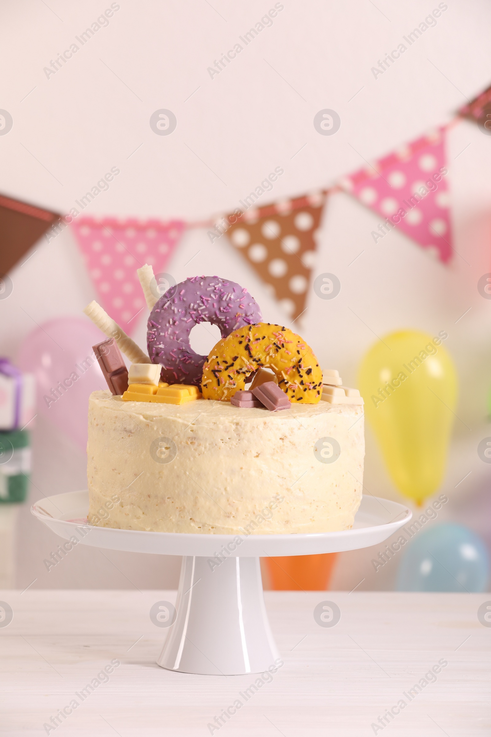 Photo of Delicious cake decorated with sweets and balloons on white wooden table, space for text