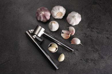 Photo of Garlic press, bulbs and cloves on grey table, flat lay