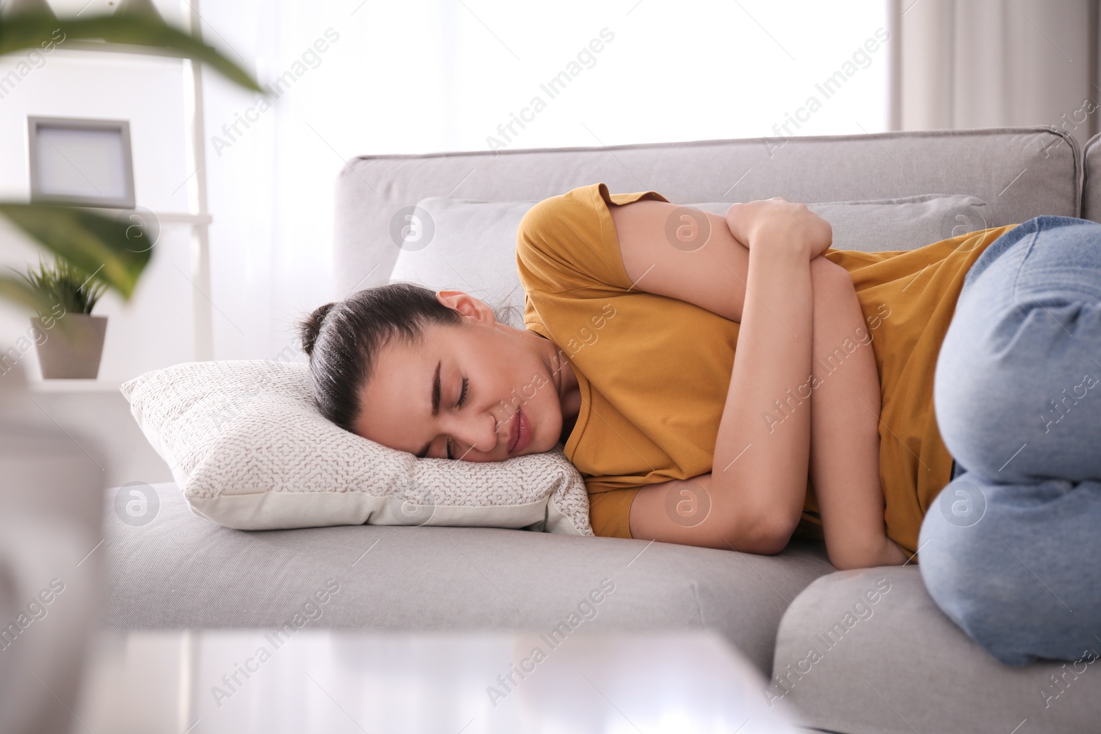 Photo of Young woman suffering from stomach ache at home. Food poisoning