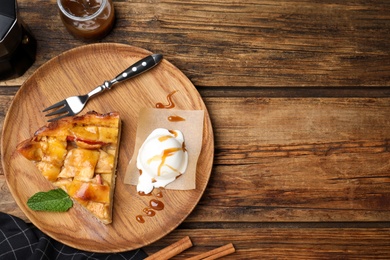 Slice of traditional apple pie with ice cream and mint on wooden table, flat lay. Space for text