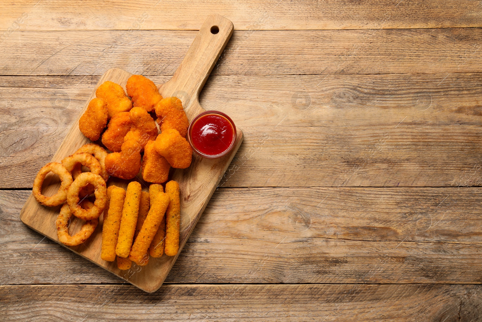 Photo of Board with tasty ketchup and different snacks on wooden table, top view. Space for text