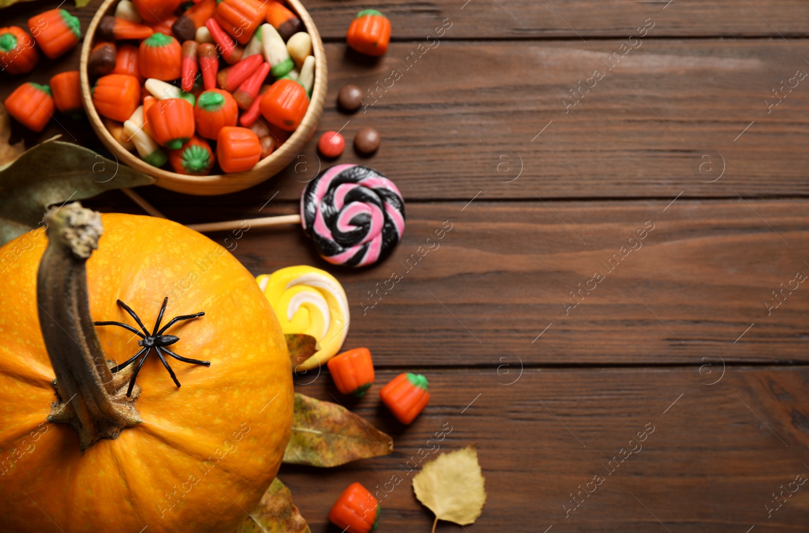 Photo of Flat lay composition with pumpkin head Jack lantern and Halloween treats on wooden background. Space for text