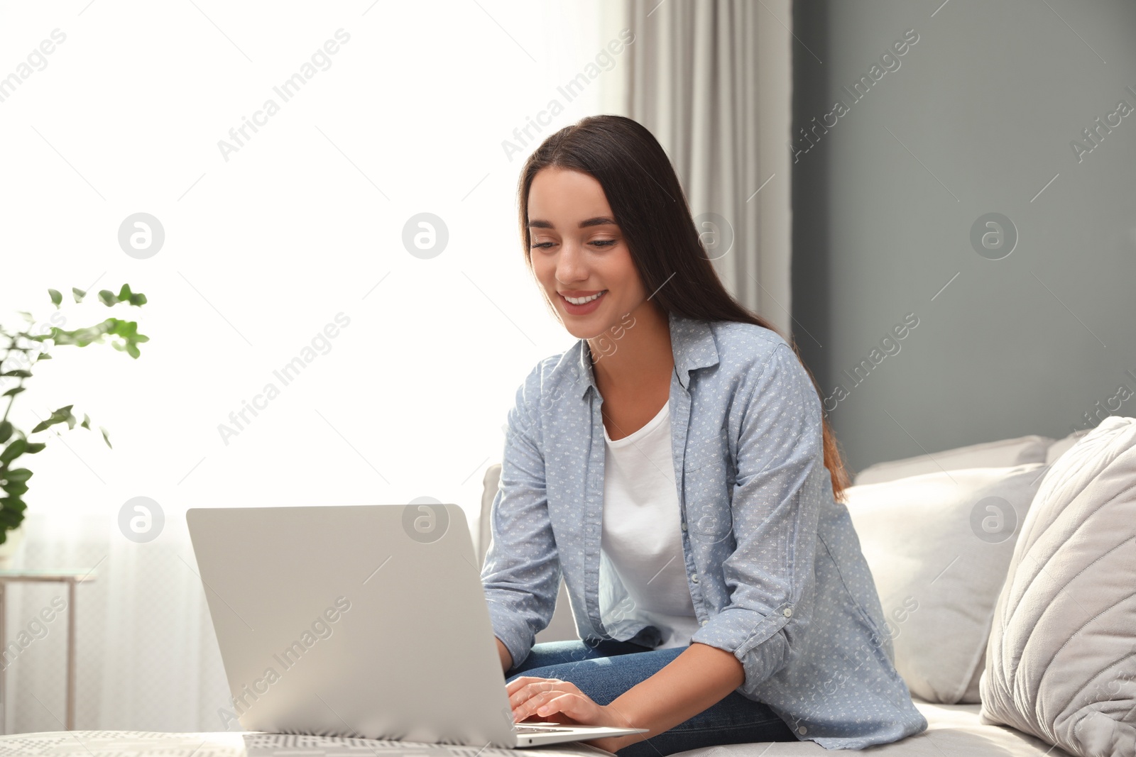 Photo of Young woman using laptop for search at home