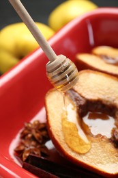 Photo of Pouring tasty honey onto baked quinces in dish on table, closeup