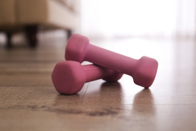 Photo of Pink dumbbells on floor in room, closeup. Home fitness