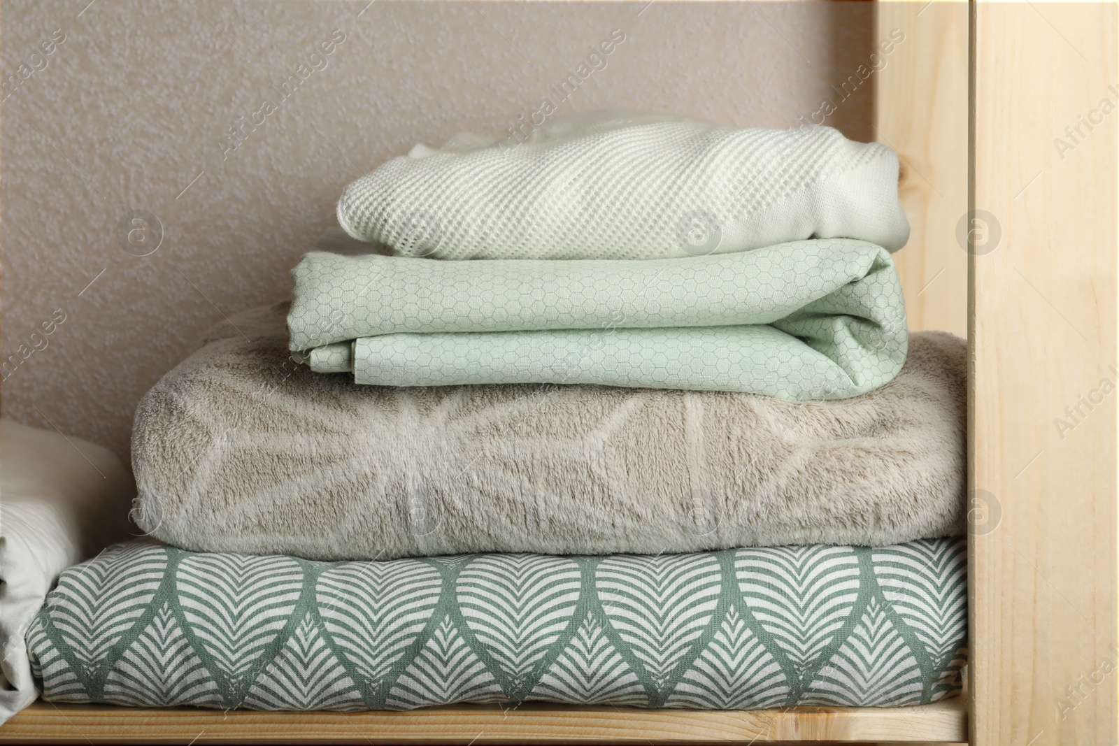 Photo of Different soft towels on wooden shelf indoors