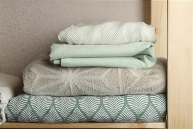 Different soft towels on wooden shelf indoors