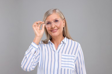 Portrait of beautiful middle aged woman in eyeglasses on light grey background